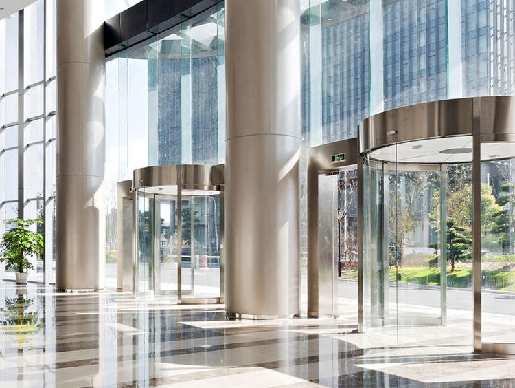 Interior view of corporate office building entry, multiple glass revolving doors awaiting workers