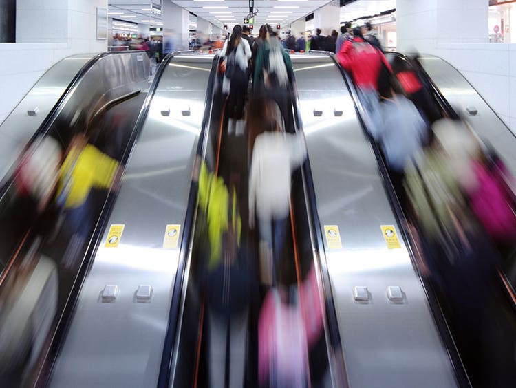 Blurred image of people riding escalator up and down